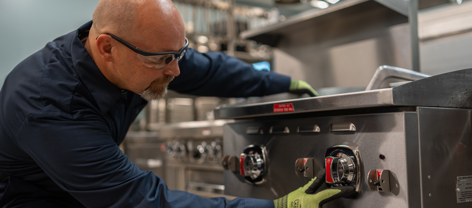 Technician adjusting the control knobs on a commercial range