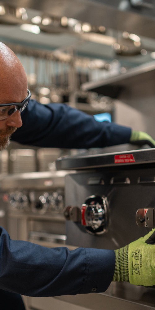 Technician adjusting the control knobs on a commercial range