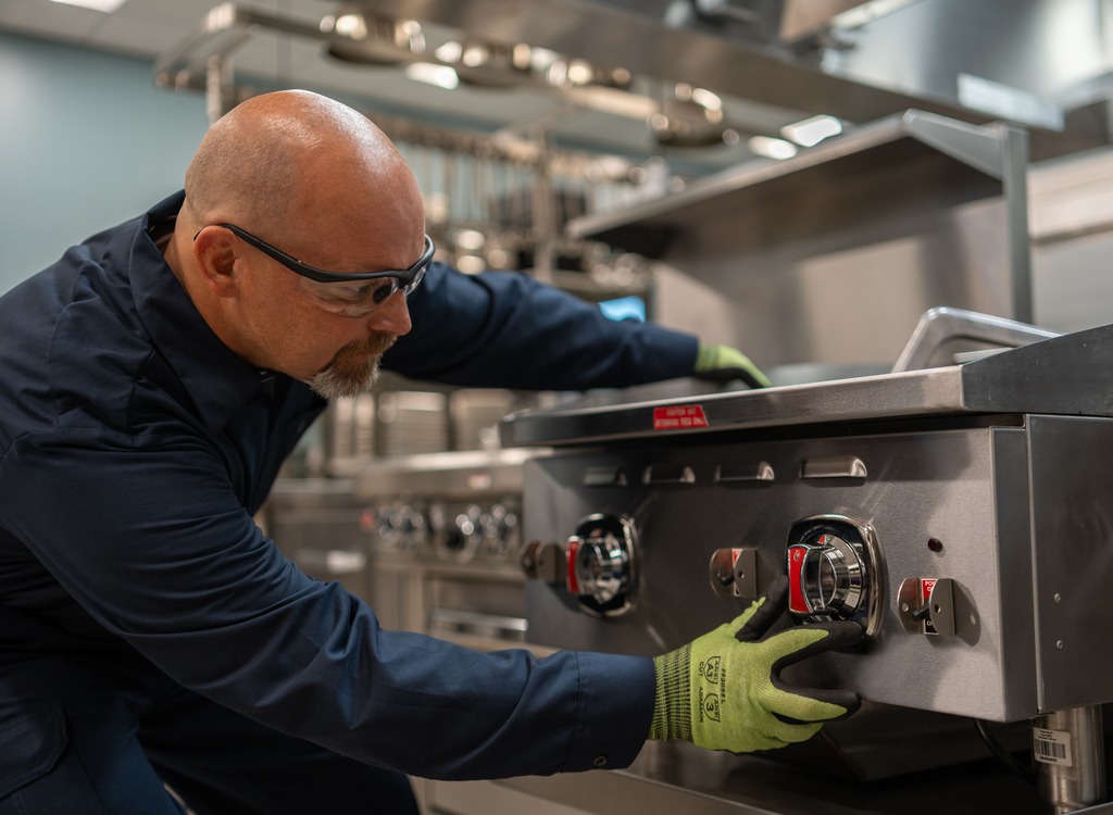 Technician adjusting the control knobs on a commercial range