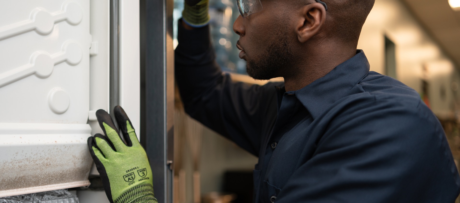 Technician using a flashlight to inspect the door seal of a commercial appliance