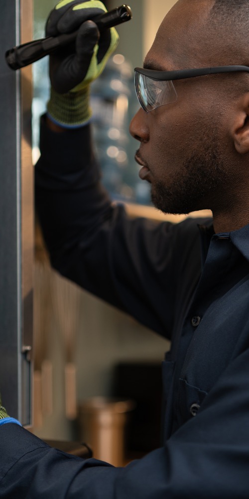 Technician using a flashlight to inspect the door seal of a commercial appliance