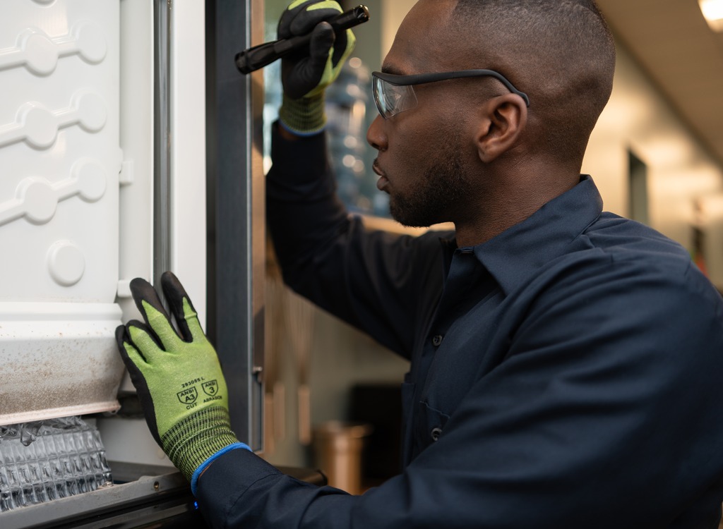 Technician using a flashlight to inspect the door seal of a commercial appliance