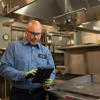 A-1 Services Group technician reviewing a service ticket on a tablet in a commercial kitchen