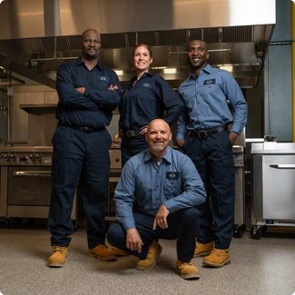 Team of four A-1 Services Group technicians posing together in a commercial kitchen