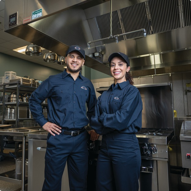A-1 Services Group technicians, a man and a woman, standing in a restaurant kitchen