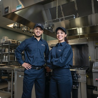 A-1 Services Group technicians, a man and a woman, standing in a restaurant kitchen