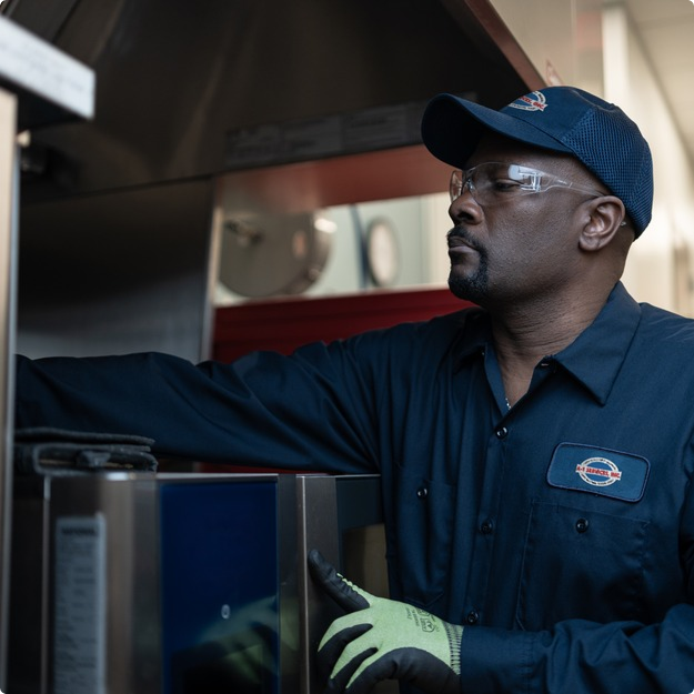 A-1 Services Group technician reaching inside a commercial kitchen appliance to service it