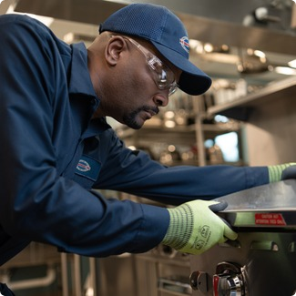 A-1 Services Group technician in safety glasses servicing a commercial cooking appliance