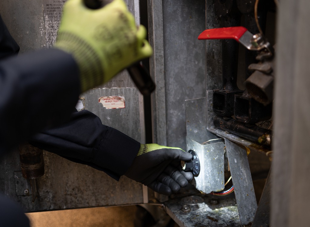 Close-up of a technician’s gloved hands repairing internal components of commercial kitchen equipment