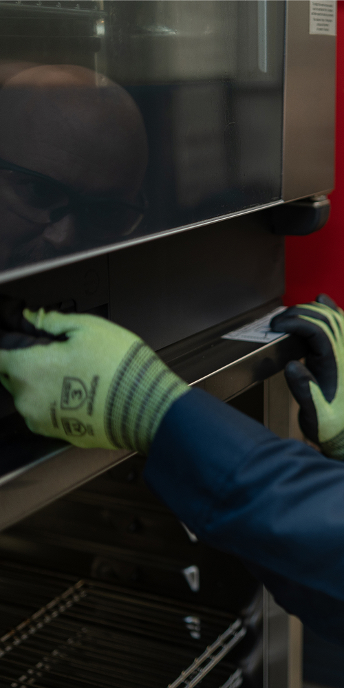 Technician in work gloves checking the door hinge of a commercial oven