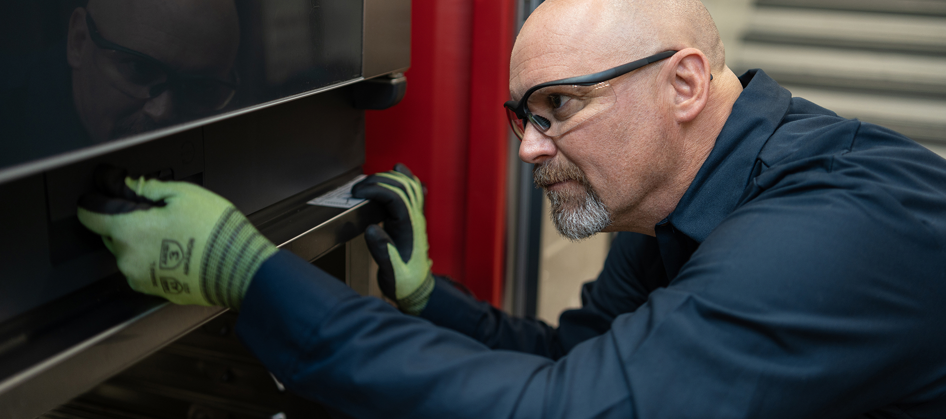 Technician in work gloves checking the door hinge of a commercial oven