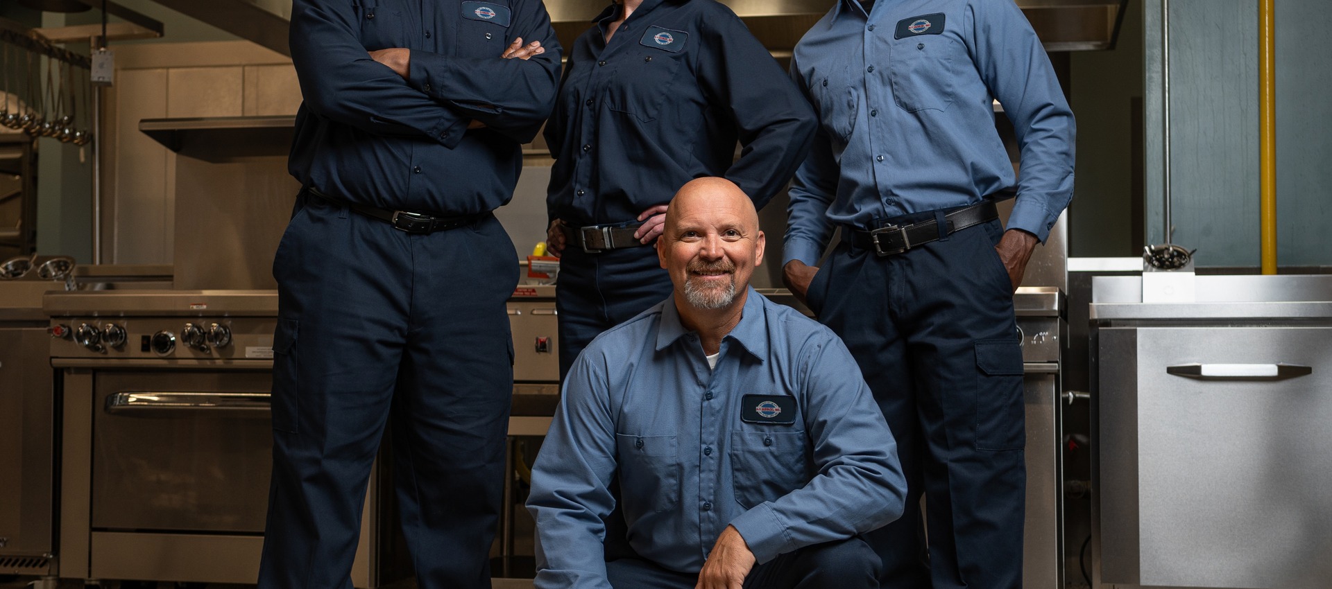 Team of four A-1 Services Group technicians posing together in a commercial kitchen