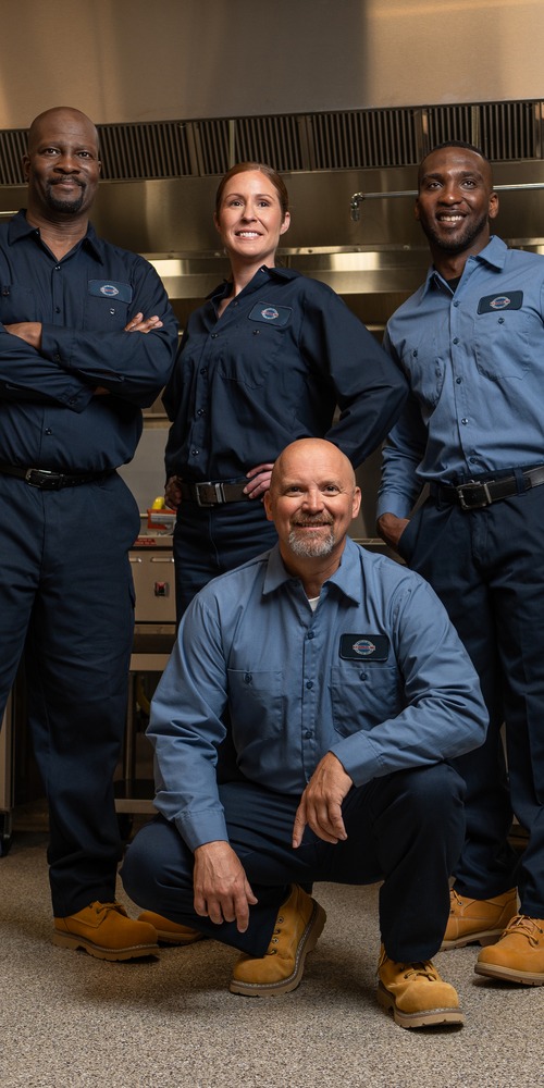 Team of four A-1 Services Group technicians posing together in a commercial kitchen