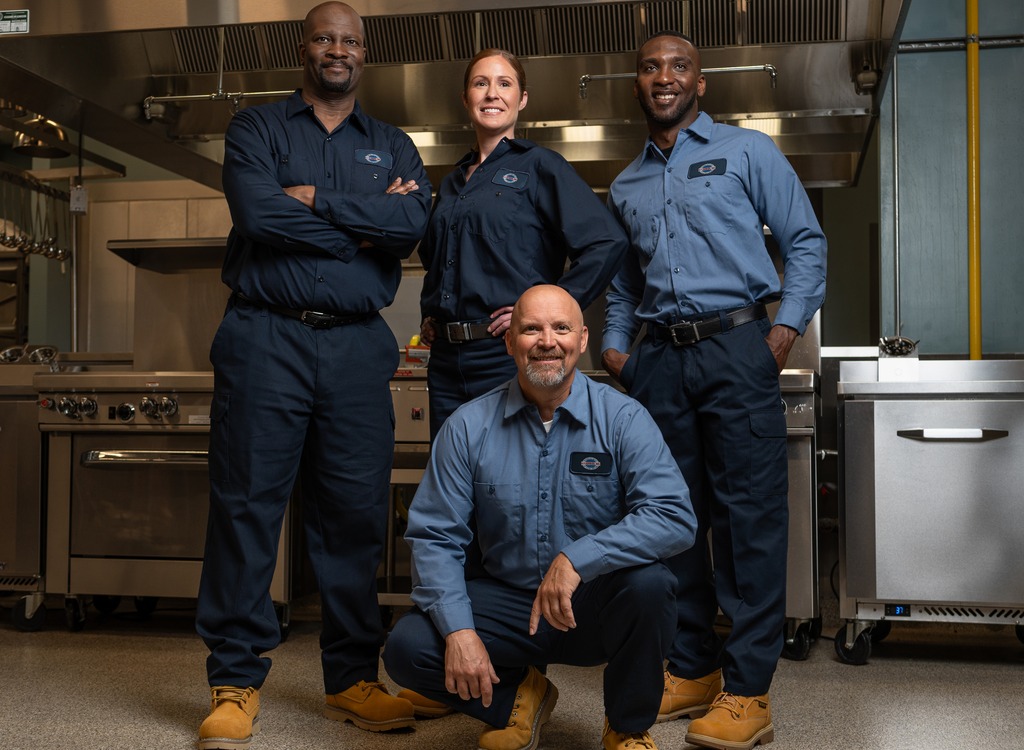 Team of four A-1 Services Group technicians posing together in a commercial kitchen