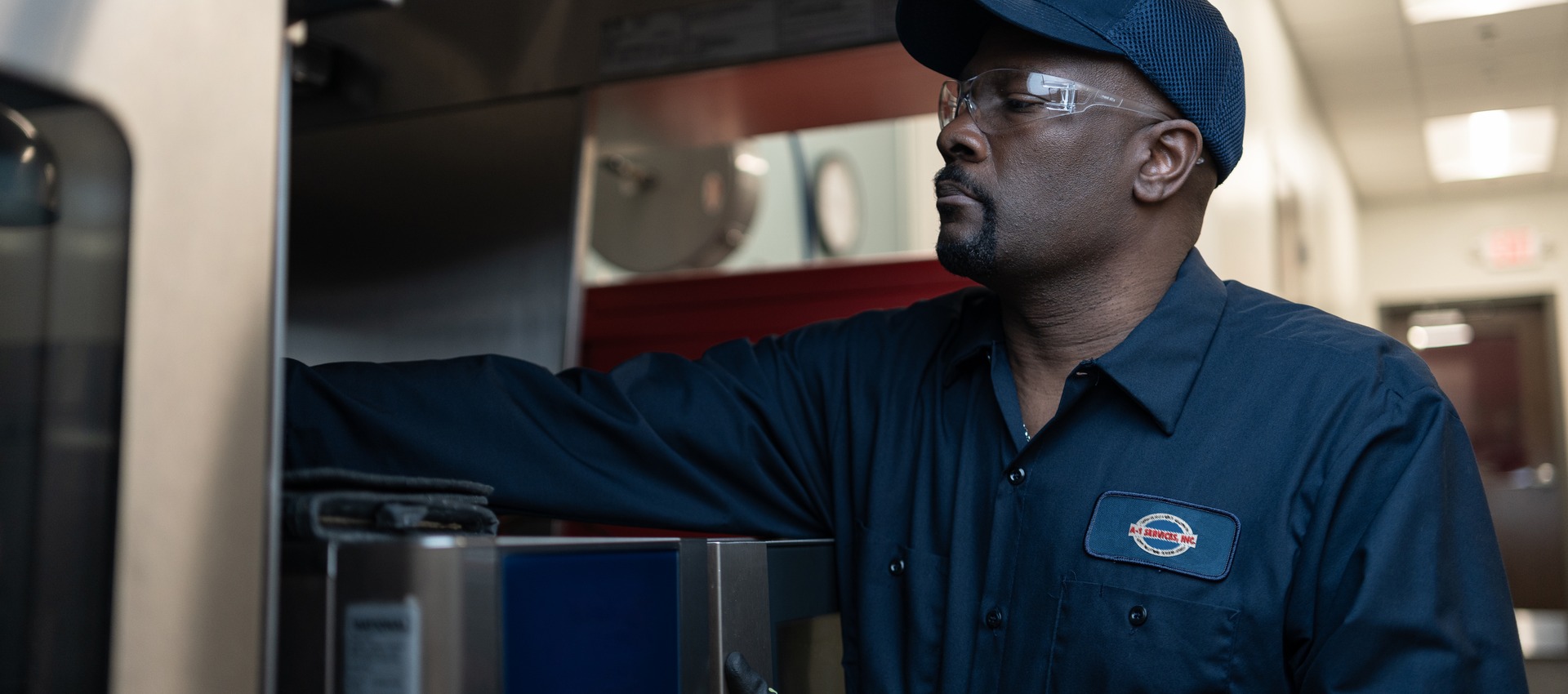 A-1 Services Group technician reaching inside a commercial kitchen appliance to service it
