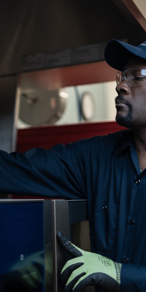 A-1 Services Group technician reaching inside a commercial kitchen appliance to service it