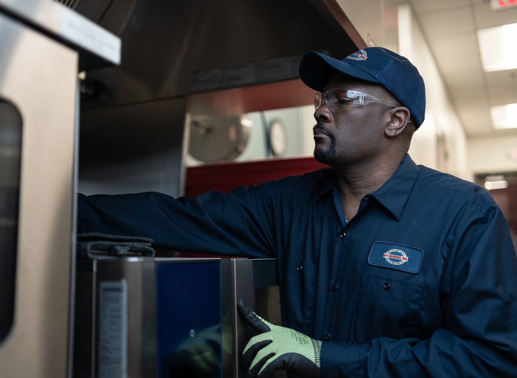 A-1 Services Group technician reaching inside a commercial kitchen appliance to service it